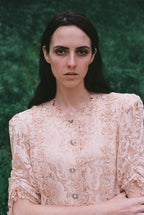 Woman wearing a lace blouse against a green background