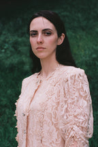 Woman wearing a beige lace blouse against a green textured background