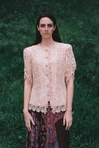 Woman wearing a lace top against a green background