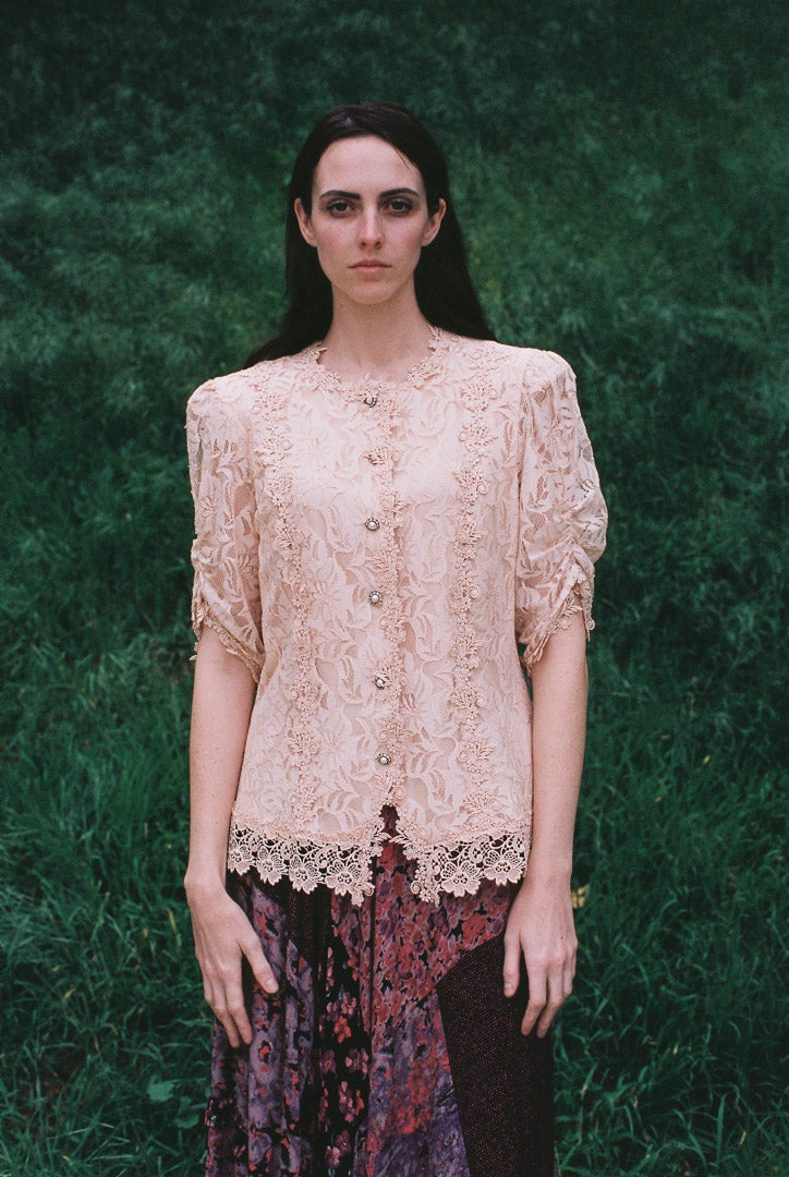Woman wearing a lace top against a green background