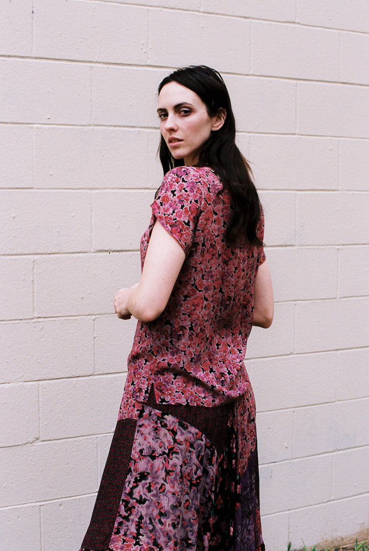 Woman wearing a floral dress against a beige wall