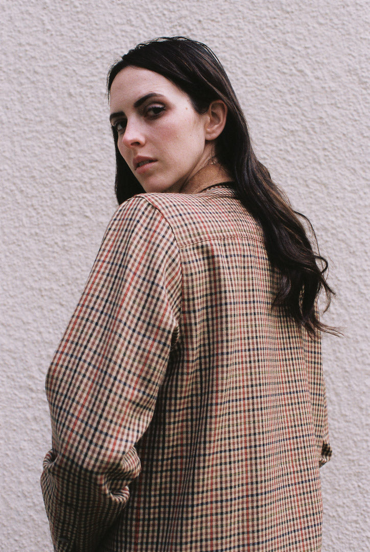 Woman wearing a plaid shirt against a light gray wall