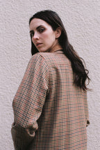 Woman wearing a plaid shirt against a light gray wall