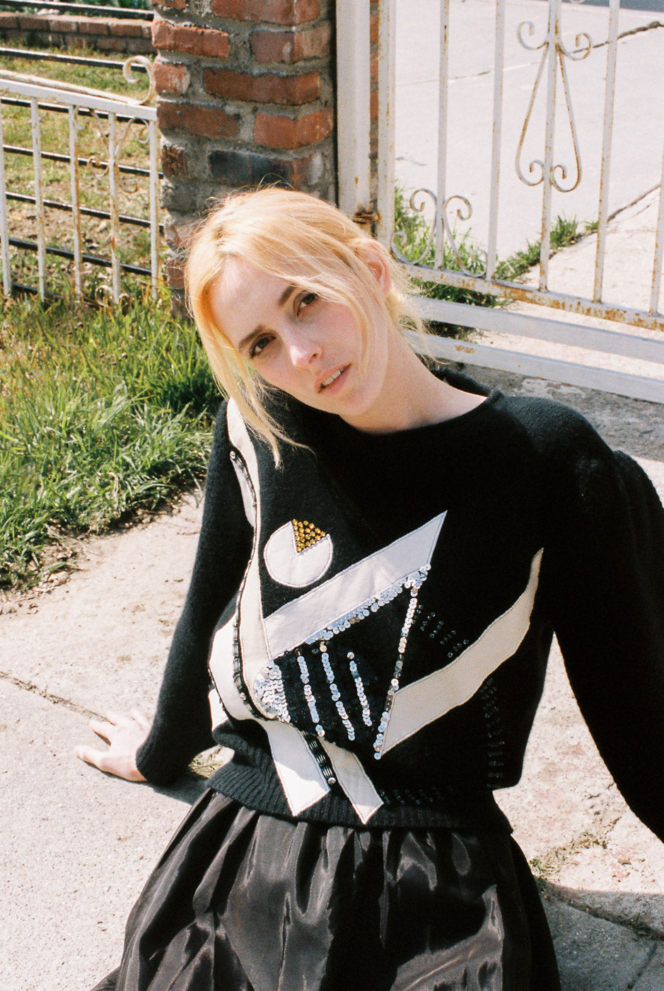 Person wearing a black sweater with white patterns outdoors