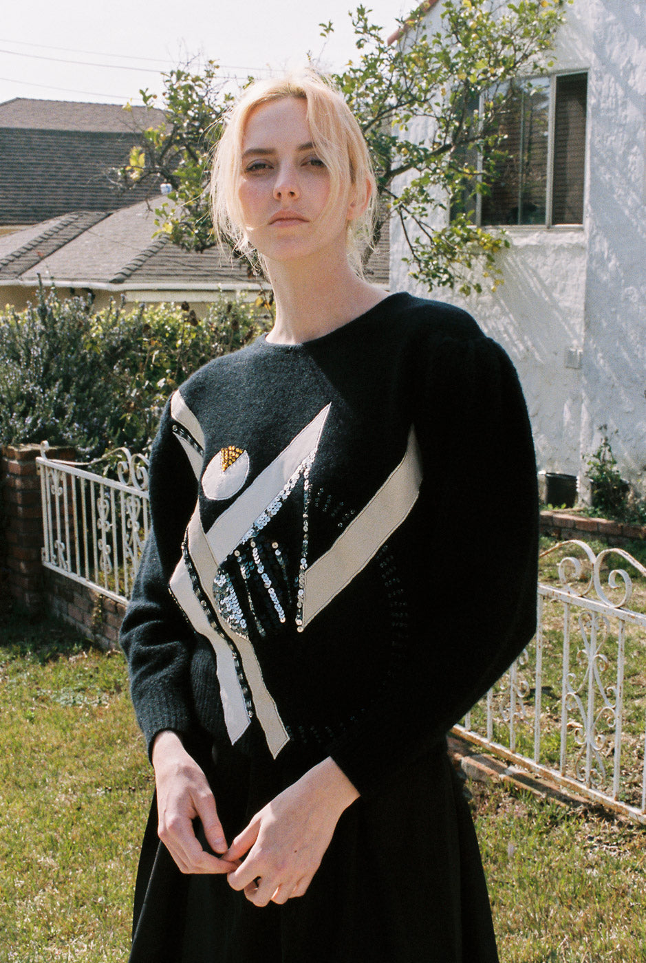 Person wearing a black sweater with a white design outdoors