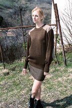 Woman wearing a brown sweater and skirt in an outdoor setting