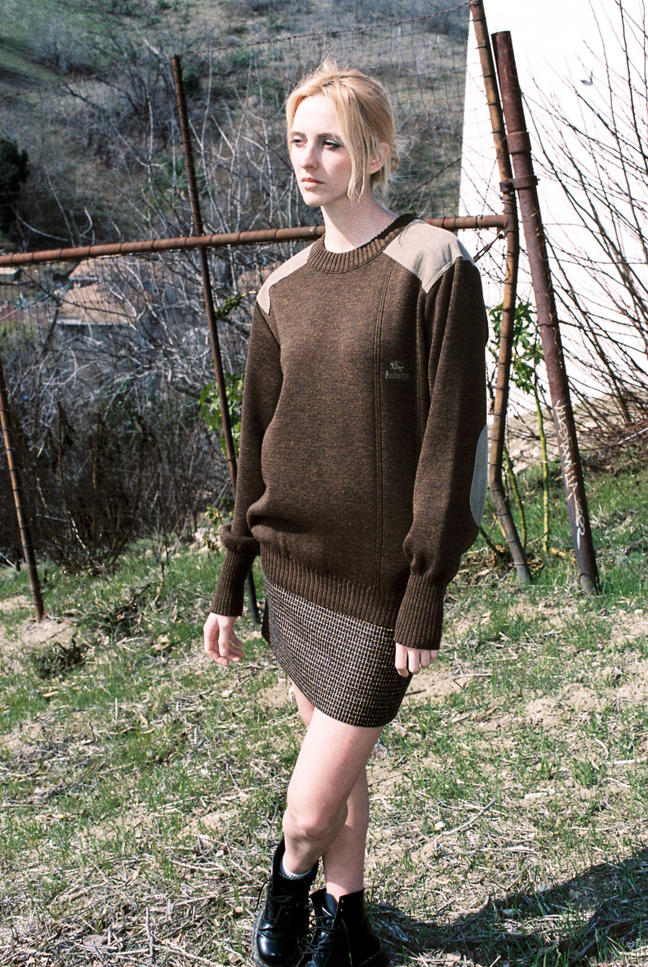 Woman wearing a brown sweater and skirt in an outdoor setting