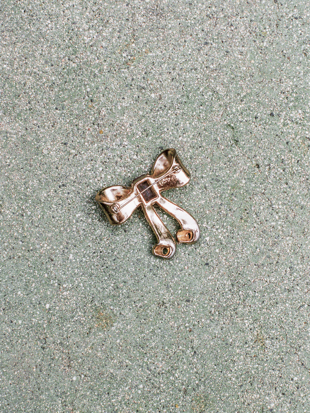 Silver bow-shaped brooch on a textured surface