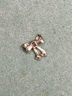 Silver bow-shaped brooch on a textured surface