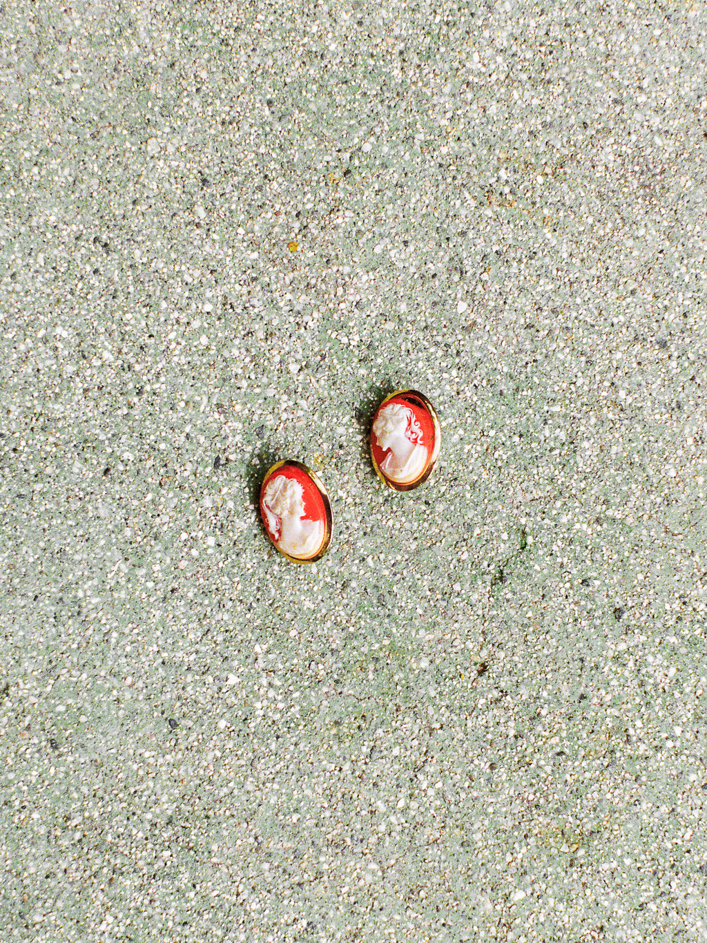 Two small red and white objects on a sandy surface