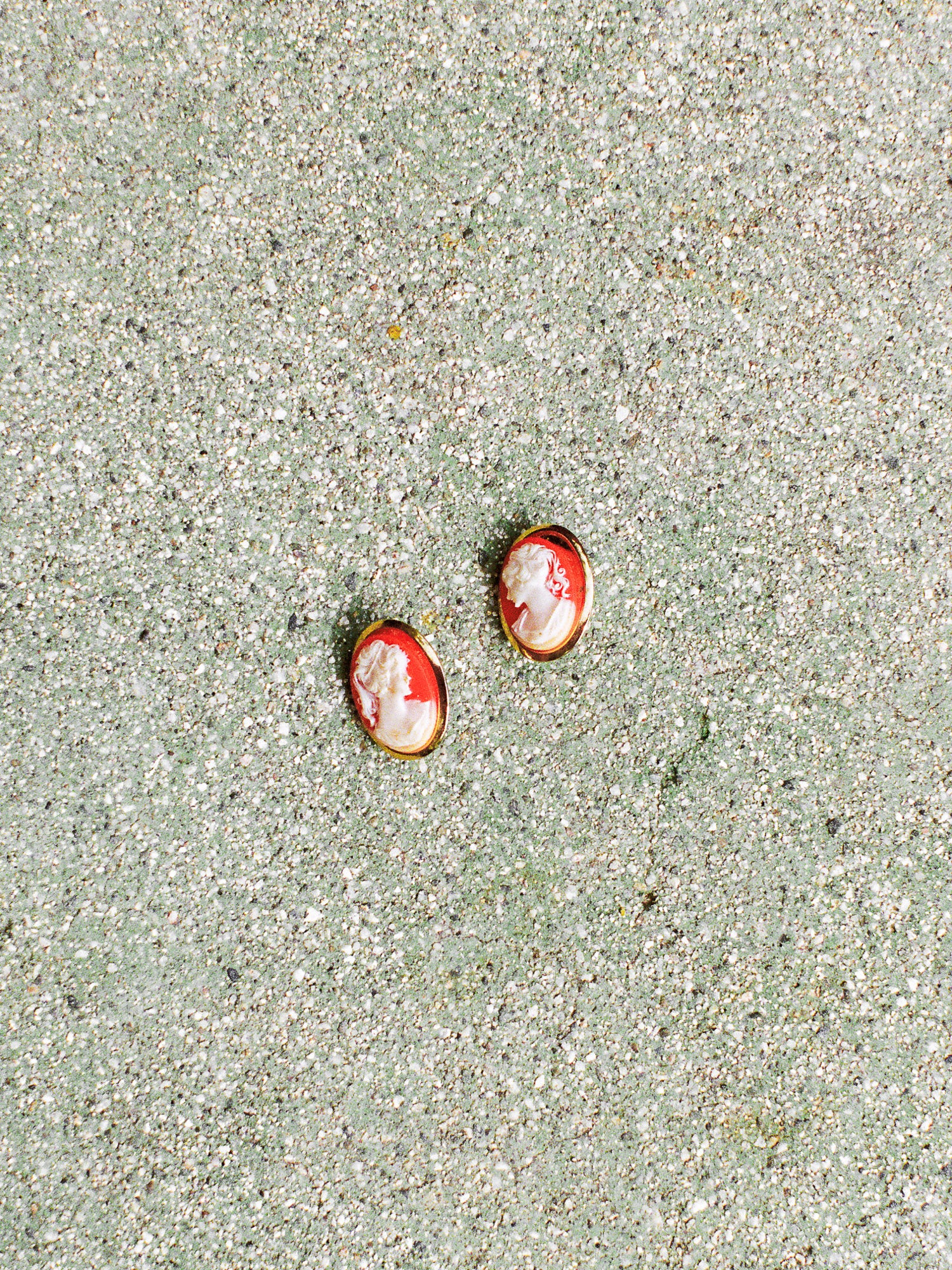 Two small red and white objects on a sandy surface