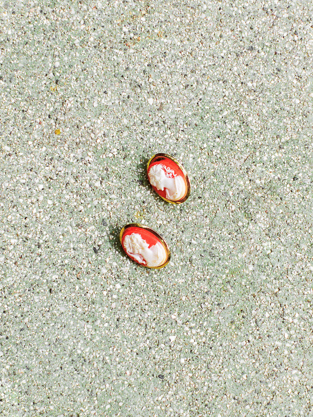 Two red and white oval objects on a sandy surface