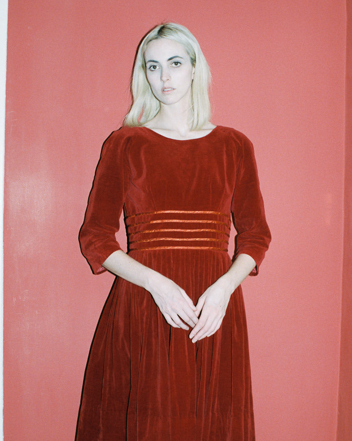 Woman wearing a red velvet dress against a pink background