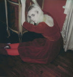 woman in a red dress sitting on the floor in a dimly lit room.