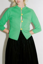 Green jacket with yellow buttons worn by a person on a white background