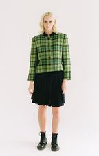Person wearing a green plaid shirt and black skirt on a white background