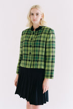 Woman wearing a green plaid jacket and black skirt on a white background