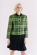 Woman wearing a green plaid jacket over a black dress on a white background