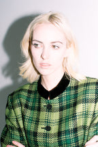 Person wearing a green plaid jacket with a plain background