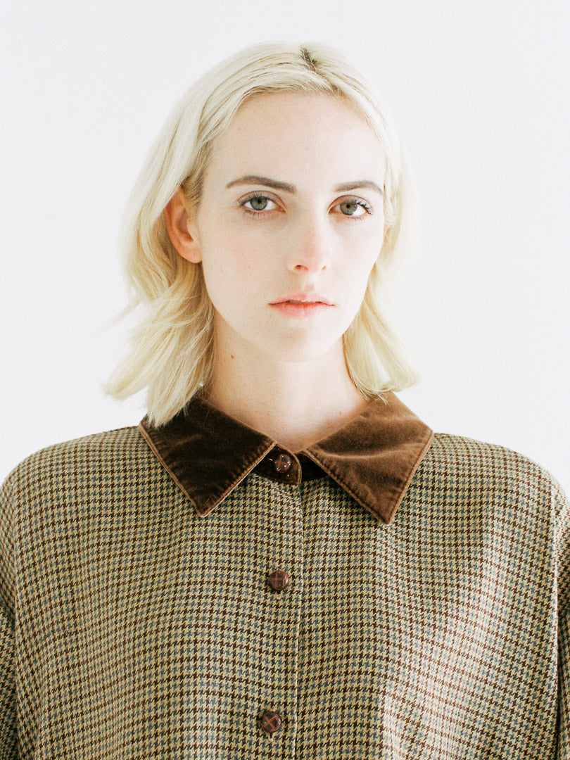 Woman wearing a checkered shirt with a brown collar against a white background