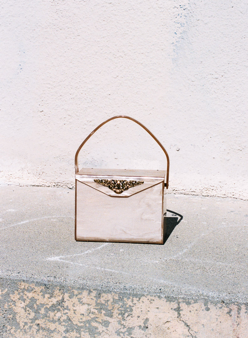 Vintage-style handbag with decorative clasp on a textured surface