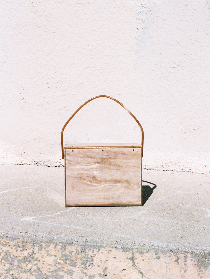 Wooden wall art piece with a gold frame on a concrete surface