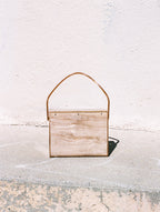 Wooden wall art piece with a gold frame on a concrete surface