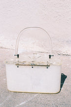 Clear handbag with a white base on a textured light gray background