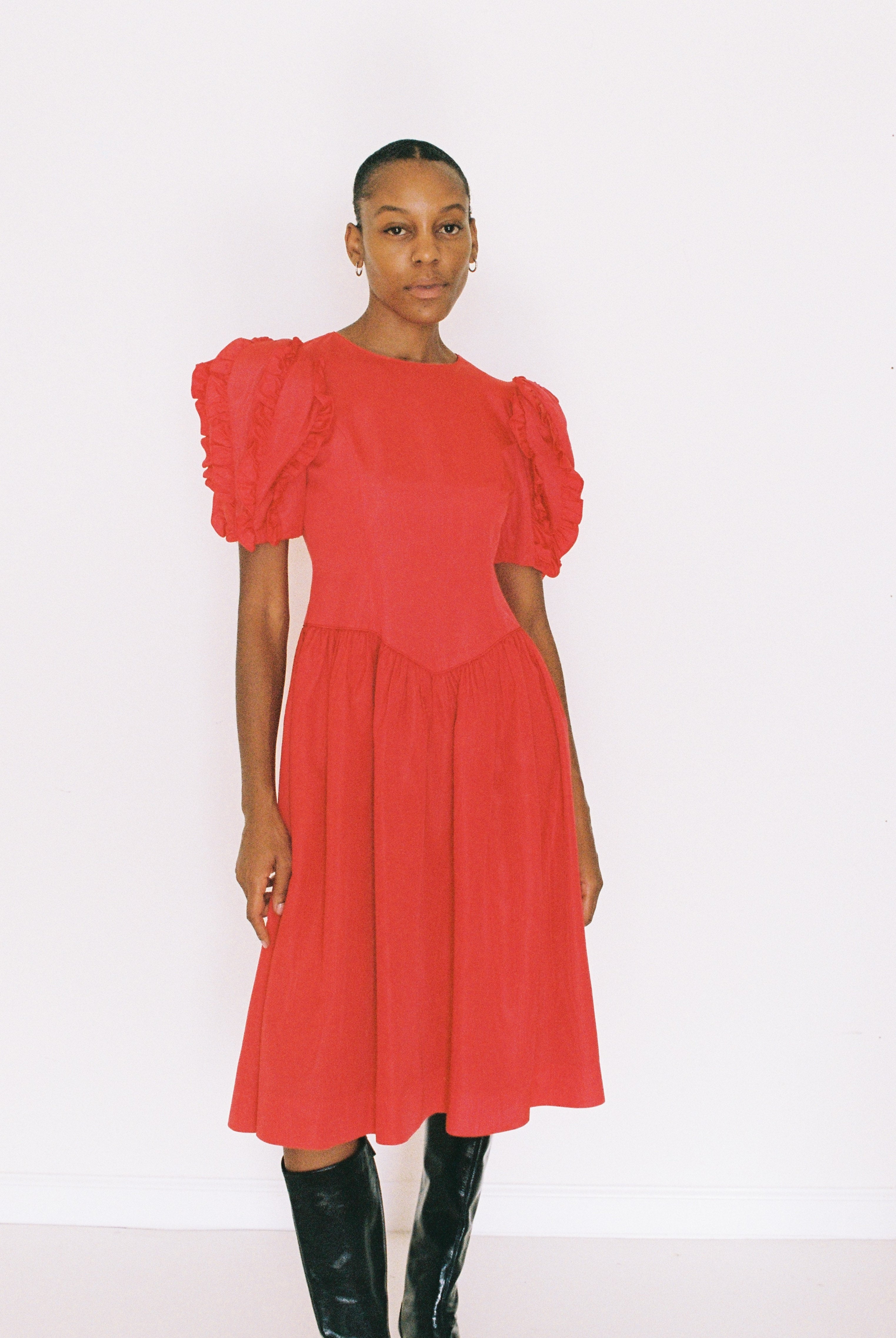 Woman wearing a red dress with puffed sleeves on a white background