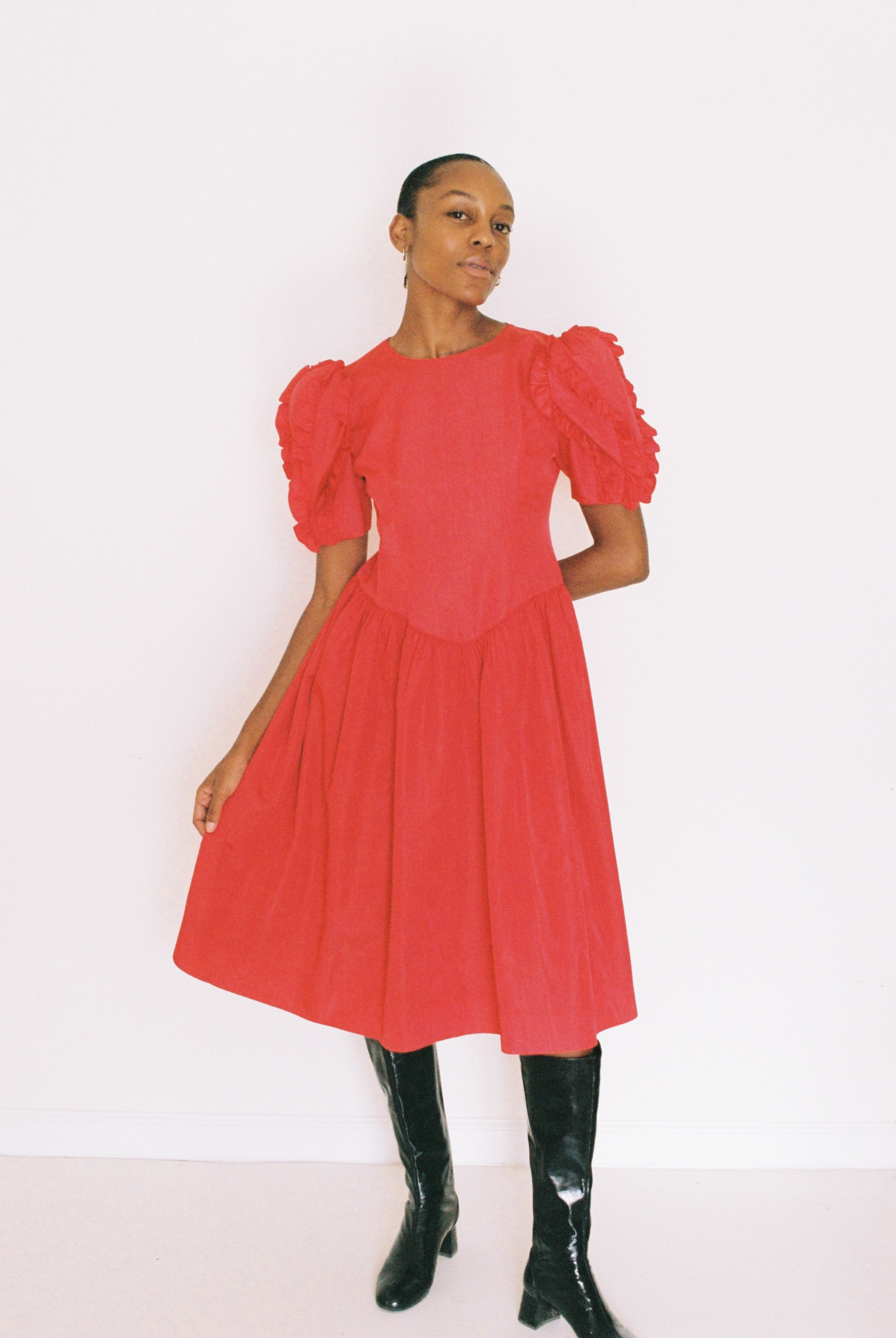 Woman wearing a red dress with puffed sleeves against a white background