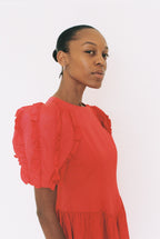 Woman wearing a red dress with puffed sleeves on a white background