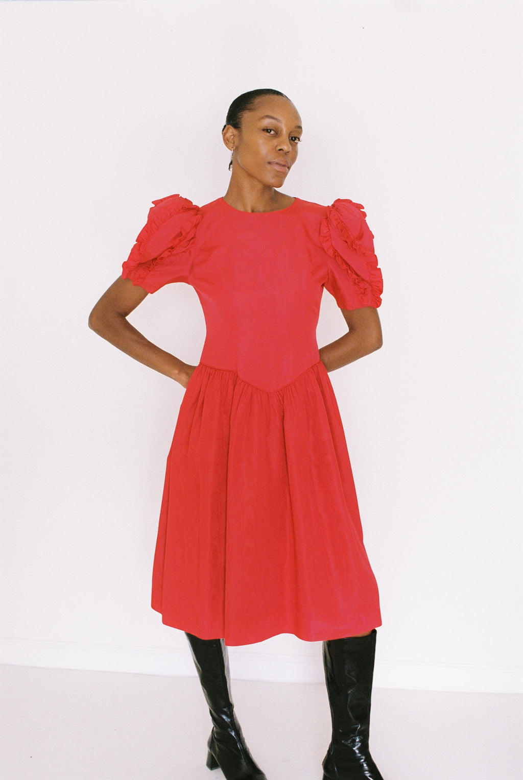 Woman wearing a red dress with ruffled sleeves on a white background