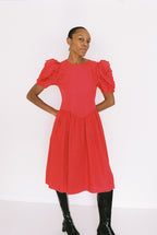 Woman wearing a red dress with ruffled sleeves on a white background