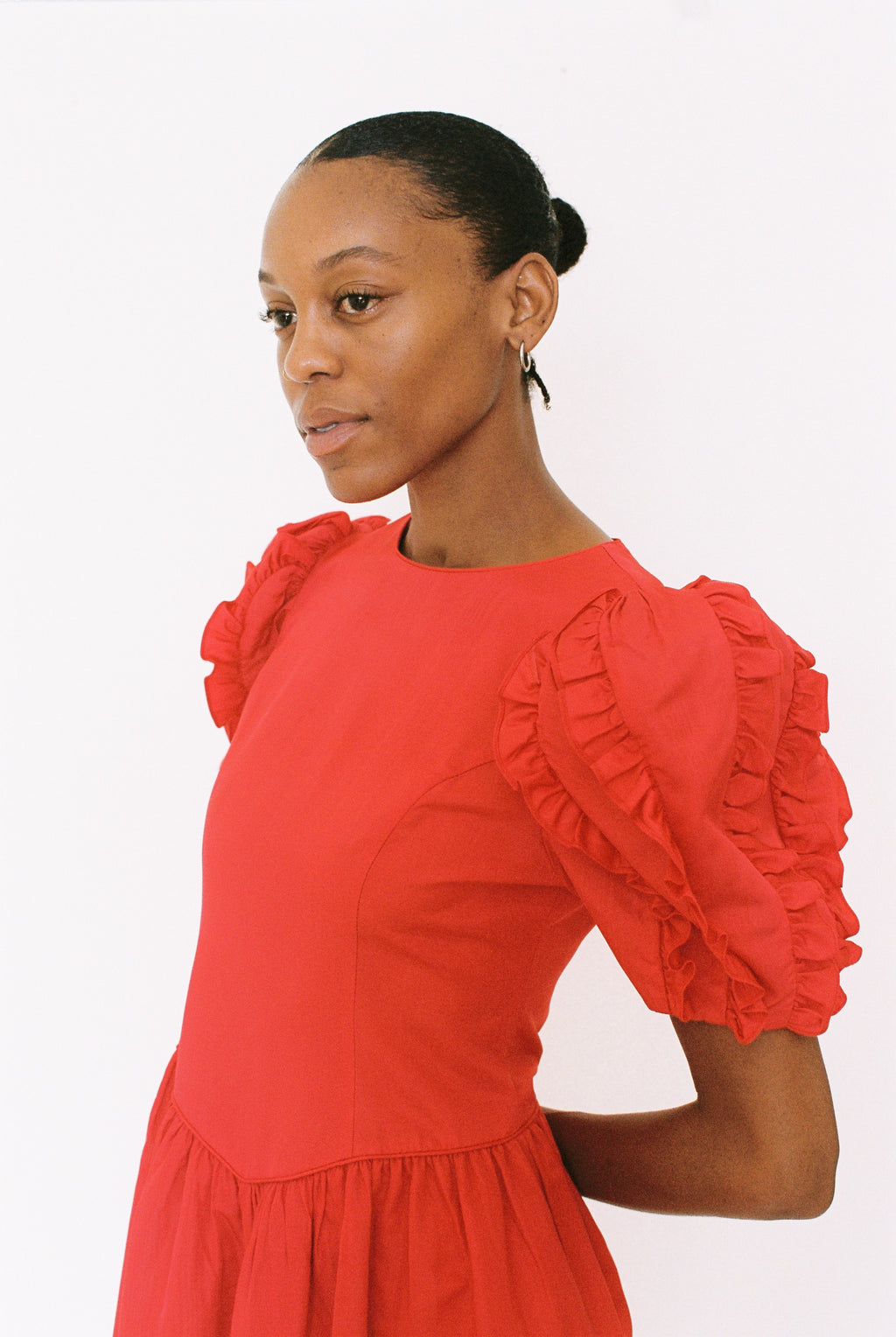 Woman wearing a red dress with ruffled sleeves on a white background