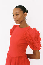 Woman wearing a red dress with ruffled sleeves on a white background