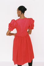 Red dress with puff sleeves worn by a person on a white background
