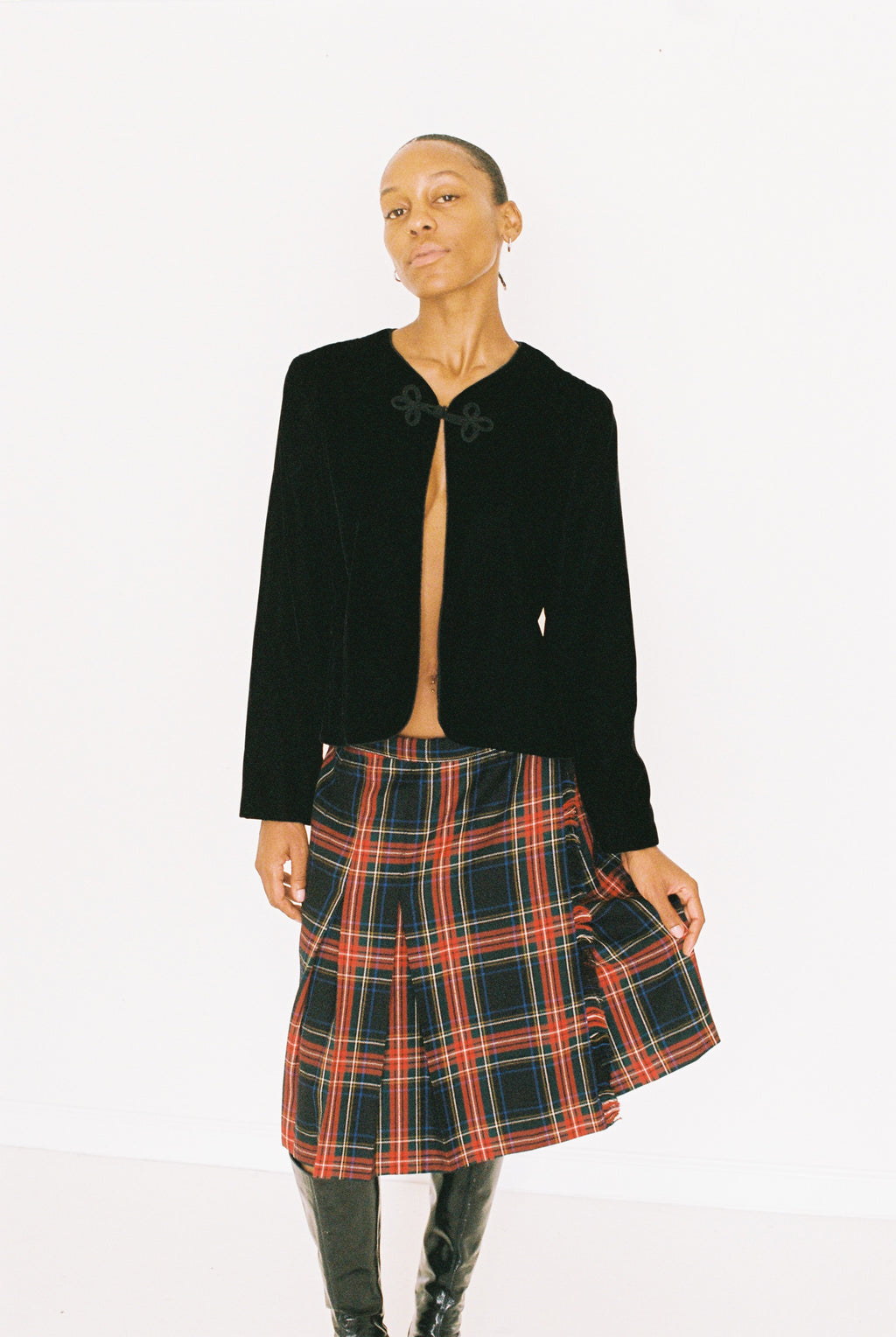 Person wearing a black jacket and plaid skirt on a white background