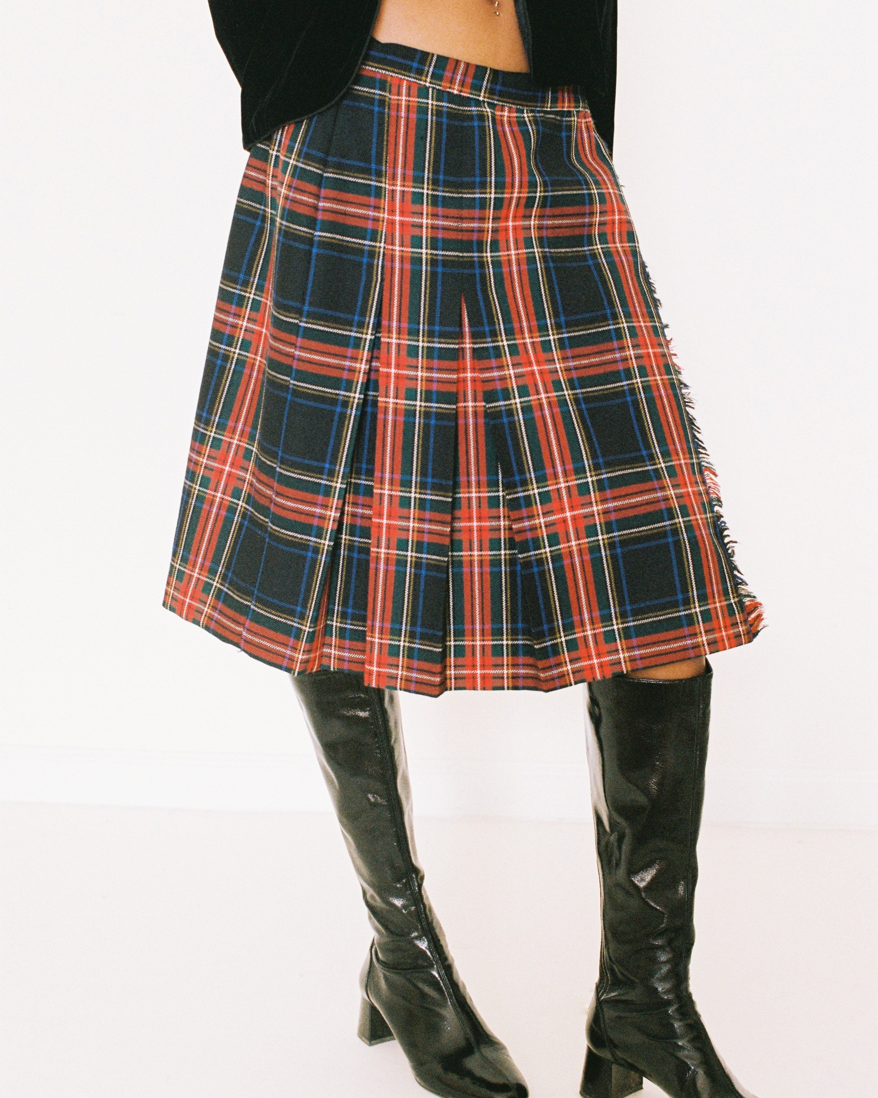 Plaid skirt worn with black boots on a white background