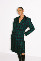 Person wearing a green and black plaid coat on a white background