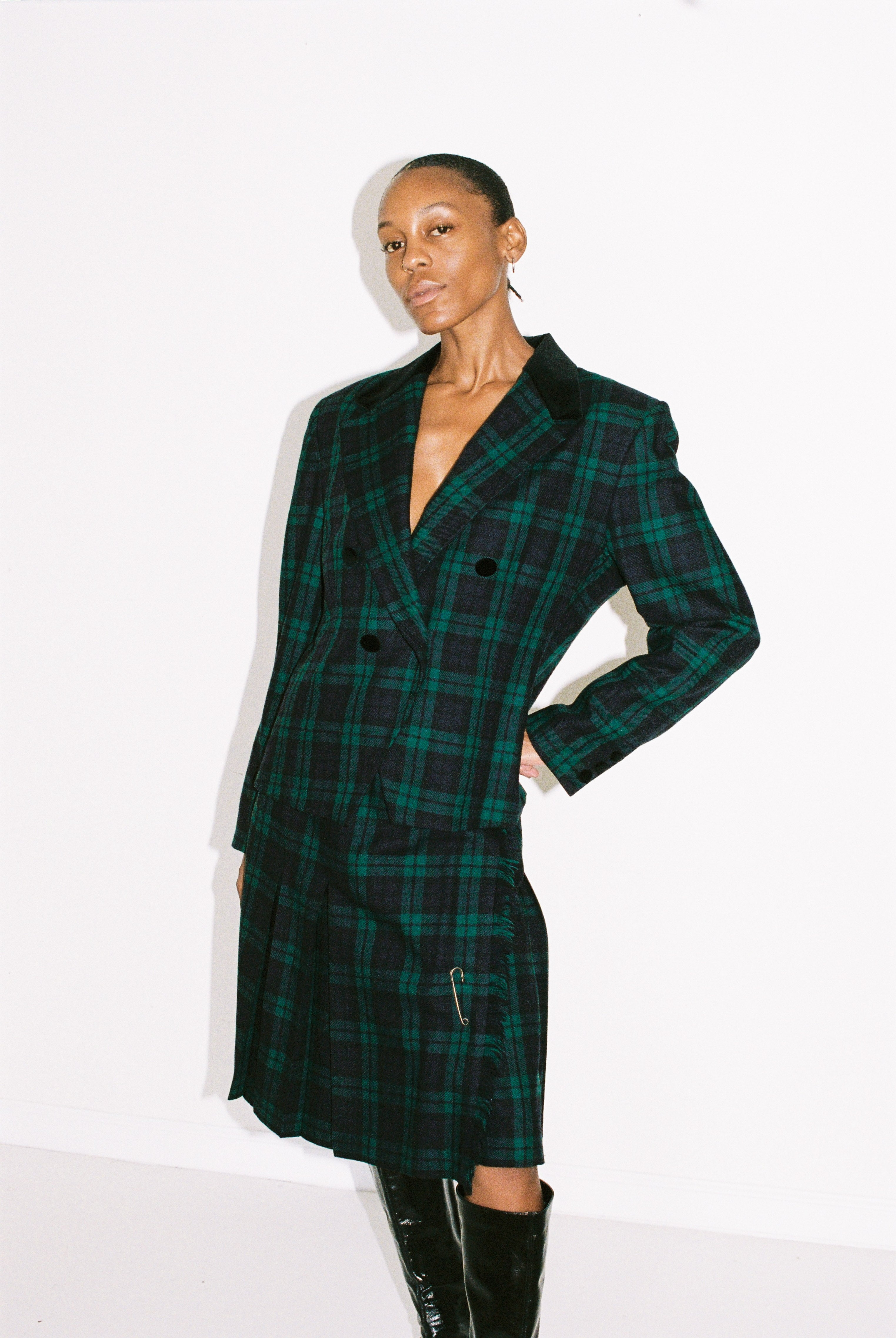 Person wearing a green and black plaid coat on a white background