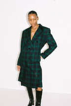 Person wearing a green plaid coat on a white background