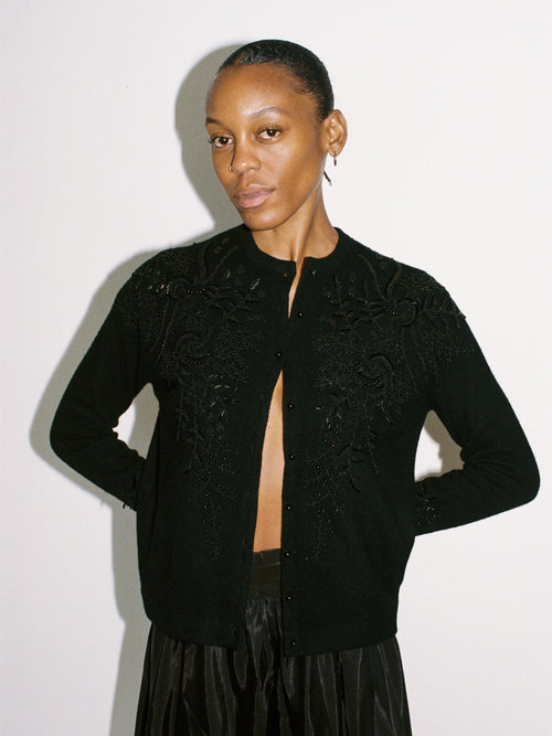 Woman wearing a black embroidered jacket against a white background