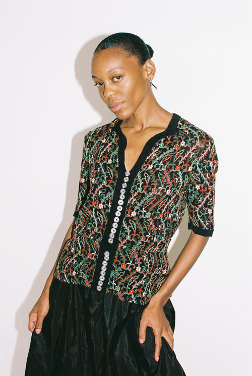 Woman wearing a patterned top with a plain background