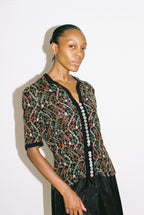 Woman wearing a patterned top with a plain background