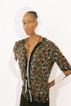 Woman wearing a floral patterned top with sequin details on a white background