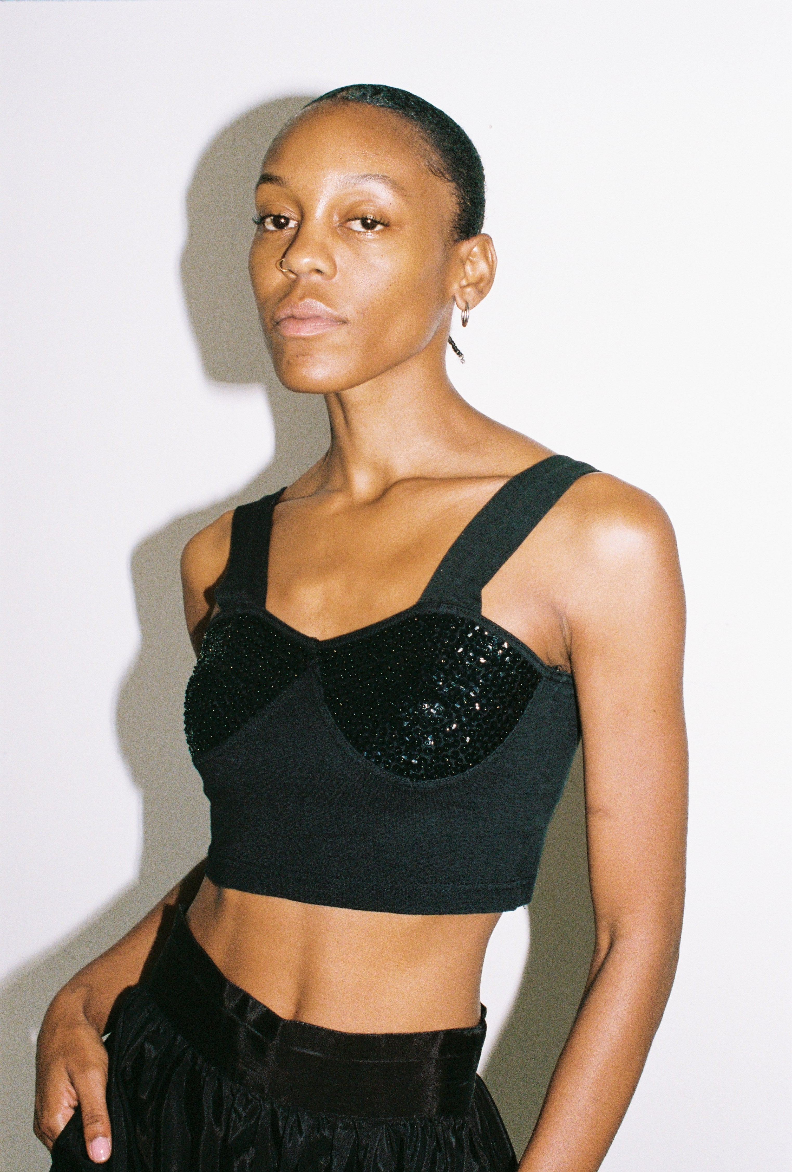 Woman wearing a black embellished top against a plain background