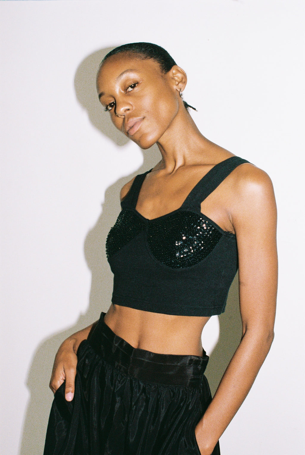Woman wearing a black top with sequin detail against a white background