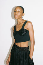 Woman wearing a black top with sequin detail against a white background