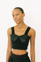 Woman wearing a black beaded top against a white background