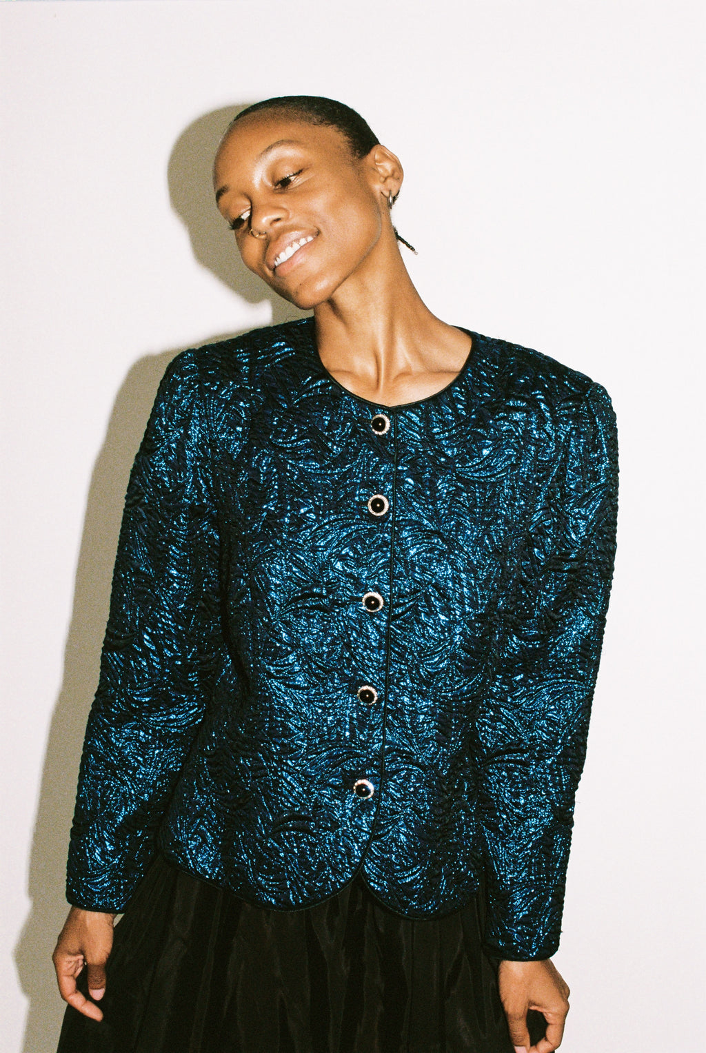 Person wearing a blue textured cardigan against a white background